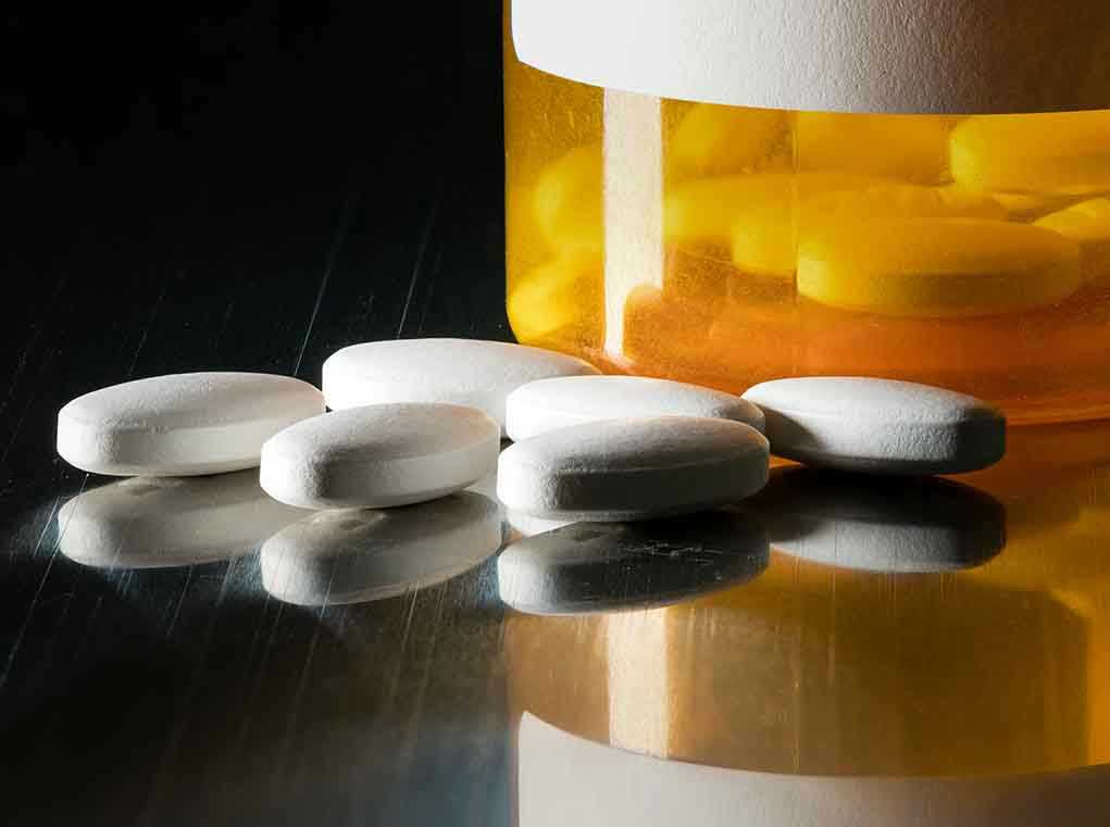 599929199 White pills beside an orange pill bottle