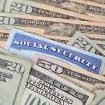 A social security card placed among various denominations of US currency