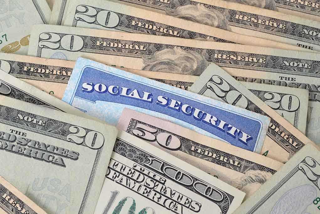 shutterstock_125374358.jpg A social security card placed among various denominations of US currency