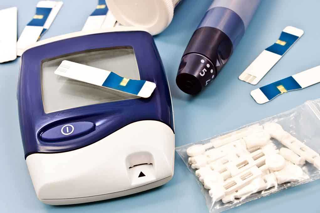 shutterstock_140662873.jpg Blood glucose monitor with testing strips and a lancing device on a blue background