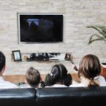 A family of four watching television together in a cozy living room