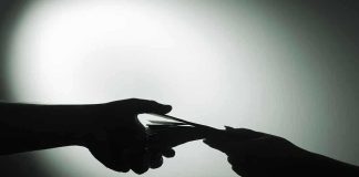 Silhouette of hands exchanging money in dim light