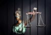 UKRAINIAN Refugee MURDERED — Negligent Judges EXPOSED Blindfolded Lady Justice statue holding scales behind bars.