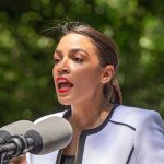 Person speaking into multiple microphones outdoors.