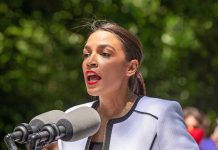 AOC’s Plans Could Shake Democratic Core Person speaking into multiple microphones outdoors.