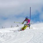Athlete skiing down a snowy slope around a slalom pole