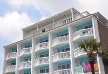Exterior view of a beachfront hotel with balconies and colorful towels hanging
