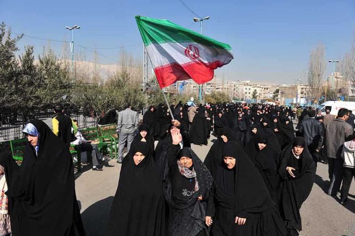 shutterstock_230251486.jpg Group of women in black attire marching with an Iranian flag