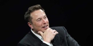 Musk’s $150B Legal Gambit CRUSHED – Shock Ruling! Man in suit smiling, resting chin on hand.