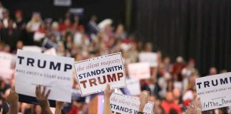 TRUMP’S Grip Tightens: Primaries Prove His Power Crowd holding signs supporting Trump at a rally.