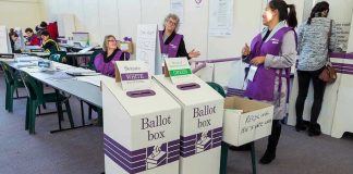 California Vote Delays Spark Debate Election polling station with ballot boxes and officials.