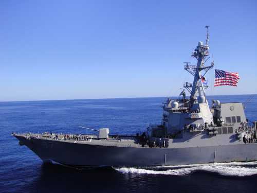 shutterstock_1133692649 A naval destroyer sailing in the ocean with an American flag