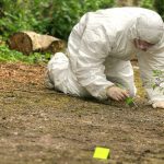 Quiet Village Shattered by Wartime Relic Blast Forensic investigator in a protective suit collecting evidence from the ground