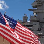 Hormuz Tensions Ignite as U.S. Intercepts Iranian Threats American flags in front of a naval ship under a blue sky