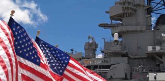 Hormuz Tensions Ignite as U.S. Intercepts Iranian Threats American flags in front of a naval ship under a blue sky