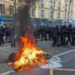Three Suspects Held After Coordinated Firebomb Attacks Fire burning on the street amid police presence.