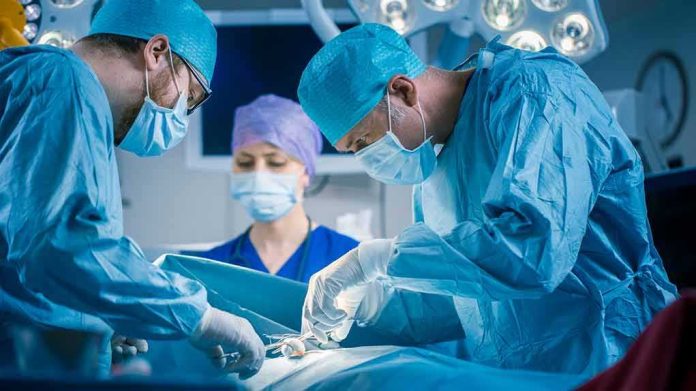 shutterstock_1152711362 Surgeons perform an operation in a hospital operating room