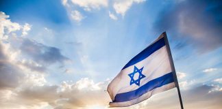 The Ceasefire Didn’t Stop the Demolitions, Says UN Israeli flag waving against a sunset backdrop with clouds