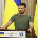 Man at a podium with Ukrainian flags