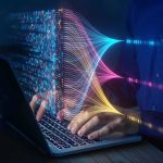 Hands typing on a laptop with colorful data streams visualized
