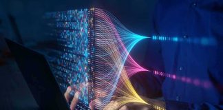 Hands typing on a laptop with colorful data streams visualized