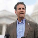man speaking at outdoor podium near government building