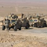 Soldiers near armored vehicles in a desert