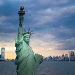 Statue of Liberty with city skyline at dusk