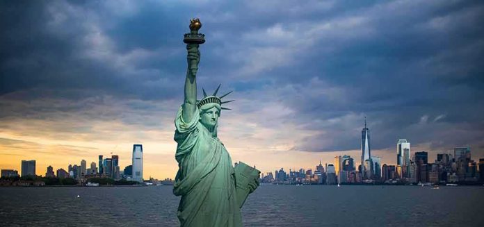 shutterstock_1157154073-1 Statue of Liberty with city skyline at dusk