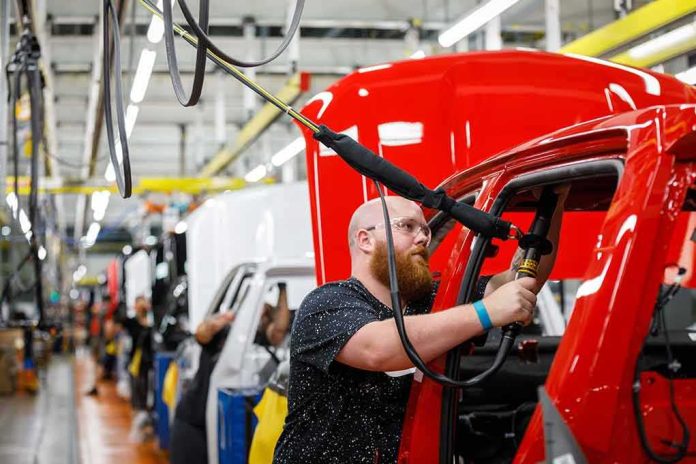 Worker assembles red vehicle on factory line