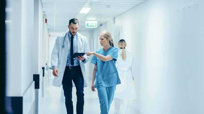 Doctors walking in a hospital corridor reviewing a tablet