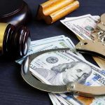 Gavel, handcuffs, and cash on a dark table