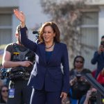 woman in navy suit waving at an outdoor event