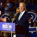 man speaking at a podium during a campaign rally