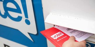 Federal Judge Freezes Trump USPS Mail-Ballot Rule Hand inserting mail-in ballot envelope into drop box