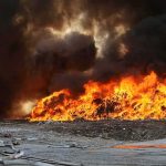 Firefighter watches large blaze with thick black smoke
