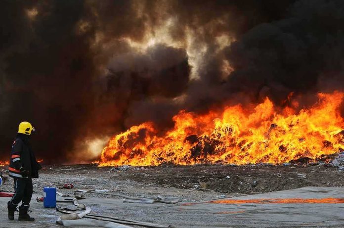 Firefighter watches large blaze with thick black smoke