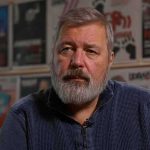 Bearded man in a blue sweater sitting indoors