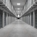 Prison corridor lined with barred cells on both sides