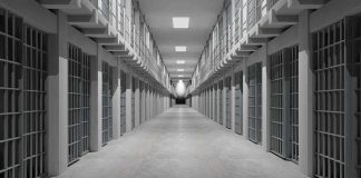 Prison corridor lined with barred cells on both sides