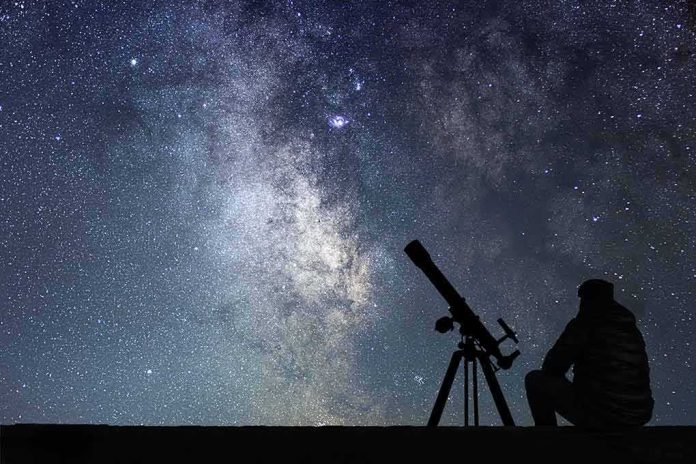 shutterstock_580851391-1 Silhouette of person with telescope under starry Milky Way sky