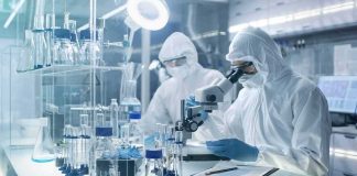 Michigan Reports First U.S. Deaths in Massive Parasite Outbreak Scientists in protective suits using a microscope in a laboratory