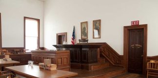 Ex-White House Staffer Fined Over Kalshi Bets Interior of a historic courtroom with wooden furniture and an American flag