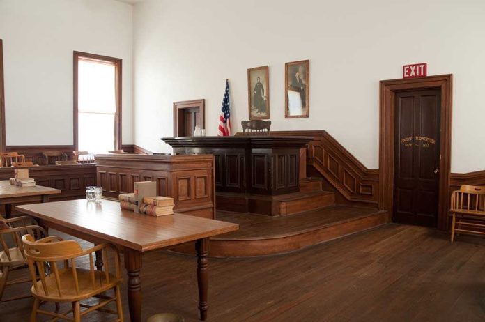 shutterstock_71233234 Interior of a historic courtroom with wooden furniture and an American flag