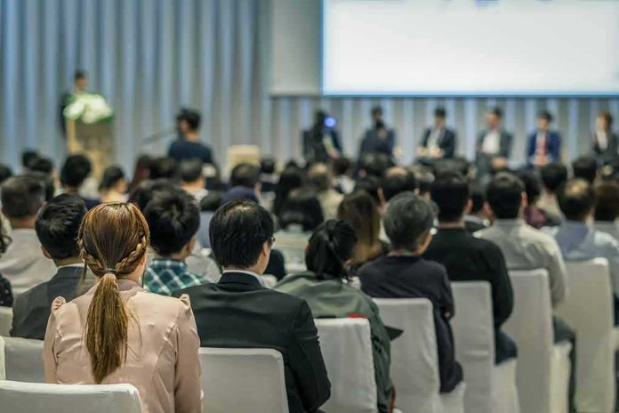 shutterstock_1029731890-1 Audience listening to a panel discussion in a conference hall