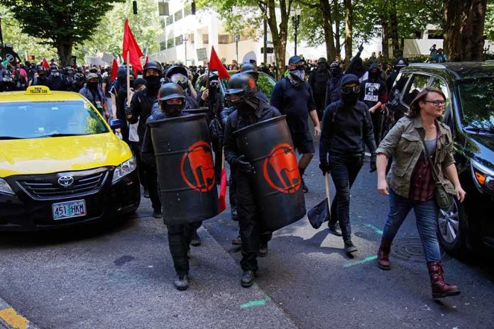 shutterstock_1246503550 masked protesters march with shields on a city street