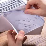 Hands opening an envelope with a check near a laptop