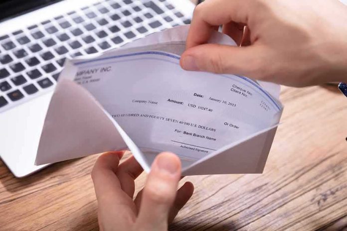 shutterstock_1315344974-1 Hands opening an envelope with a check near a laptop