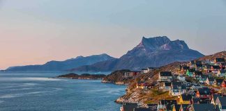 Permanent U.S. Footprint in Greenland – At What Price? Colorful coastal town with mountains and sea at sunset