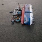 Capsized cargo ship with salvage vessels alongside
